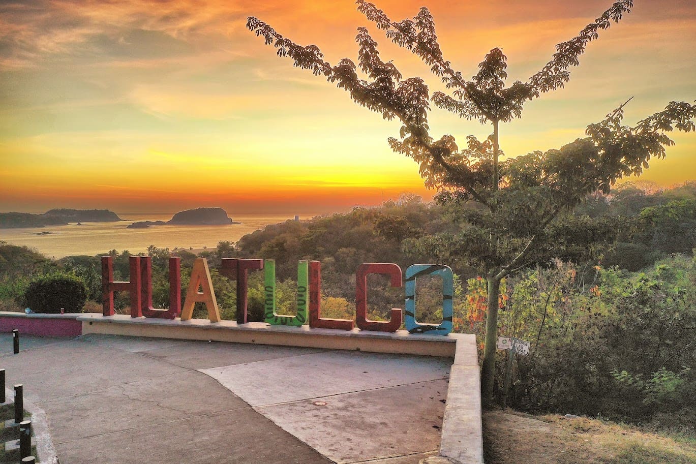 Sunset over the bays of Huatulco from the lookout with the city sign
